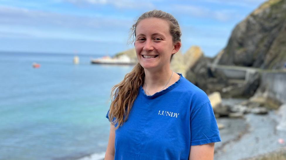 Tara McEvoy-Wilding smiling at the camera and stood in front of the sea front.