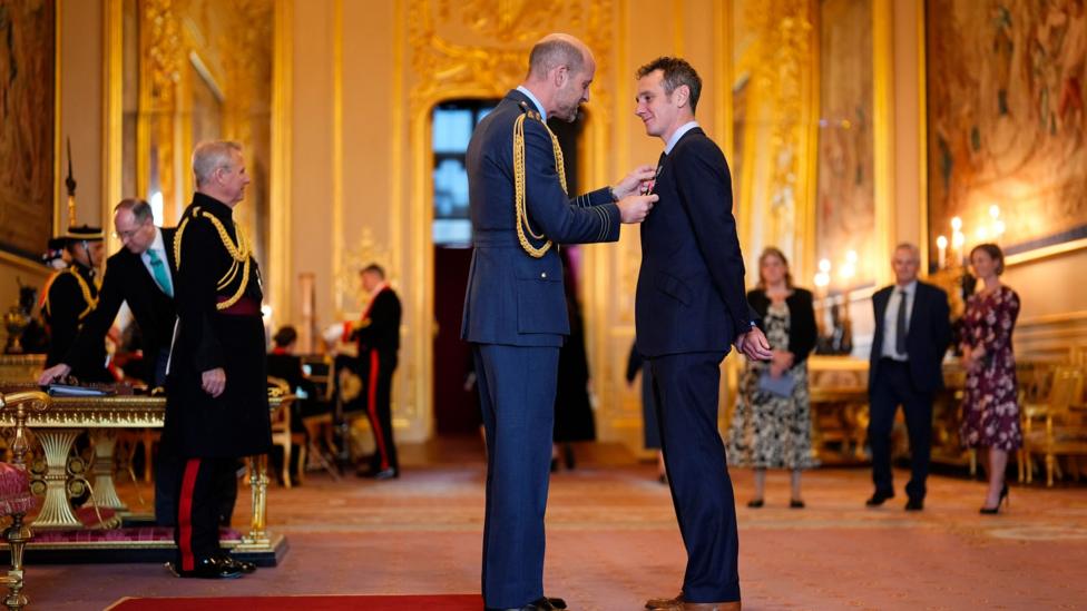 The Prince of Wales makes Alistair Brownlee an Officer of the Order of the British Empire.