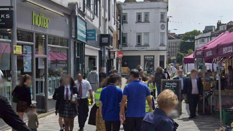 Businesses beside the market, before the fire, undamaged. People walking past