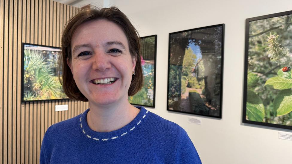Rosemary Ashworth of the Hygeine Bank with a blue jumper and a brown bob. Behind her are some pictures of nature.