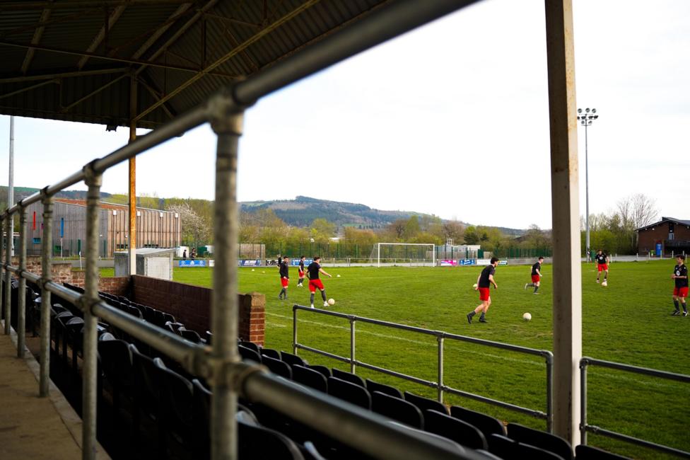 Footballers on a pitch training. The stands are in the foreground.