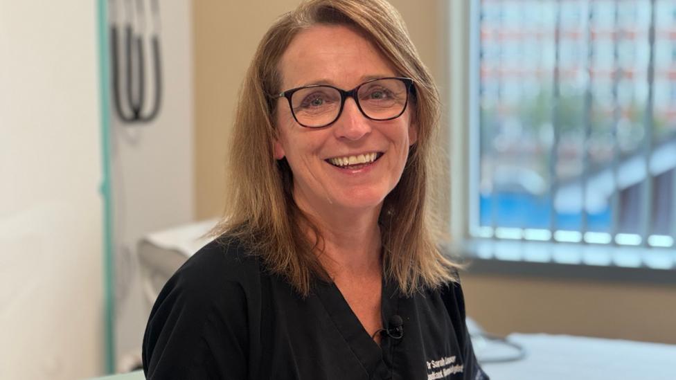 Dr Sarah Lawson smiles into camera. She is wearing a dark top.