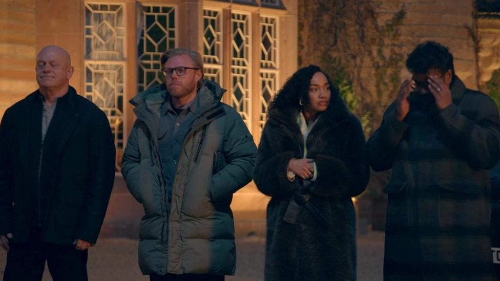 Ross Kemp, Rob Beckett, Leigh-Anne Pinnock and Romesh Ranganathan looking stressed outside the castle at night