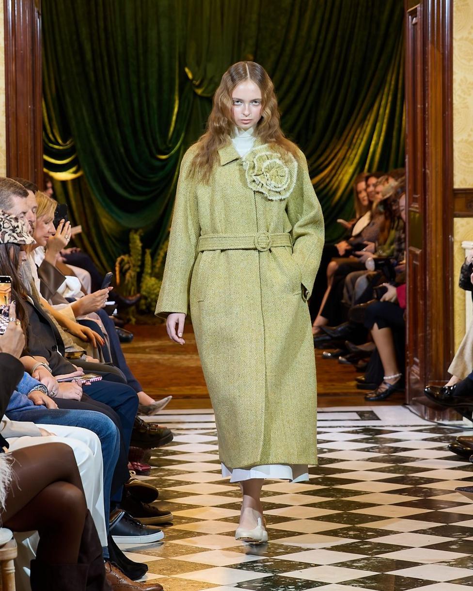 A woman on a runway, wearing a long ankle length tweed coat