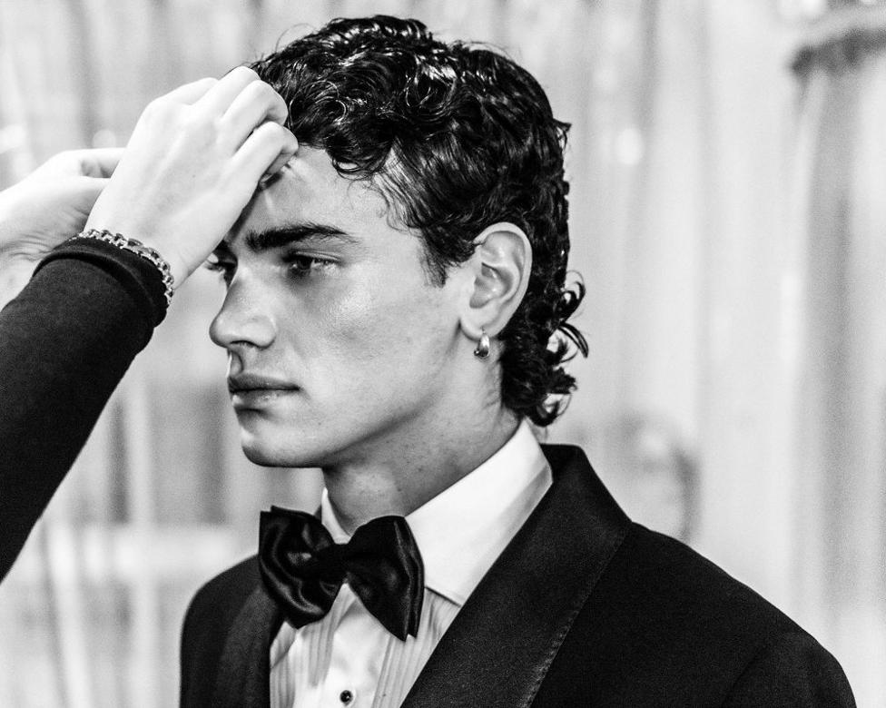 A close shot of a male model in a suit having his hair styled