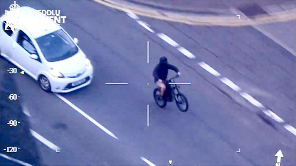 A CCTV shot watermarked Gwent Police shows a bike doing a wheelie with a masked rider.