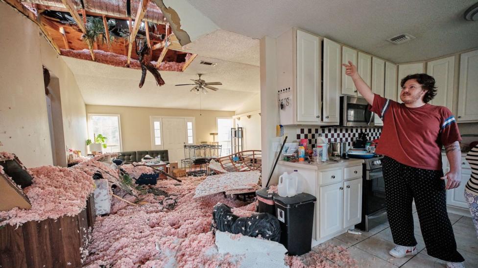 A person shows damage from the storm in their house