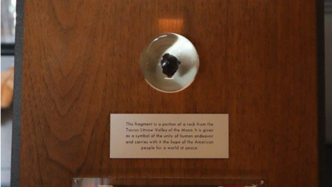 A piece of black rock set on a wooden plaque.