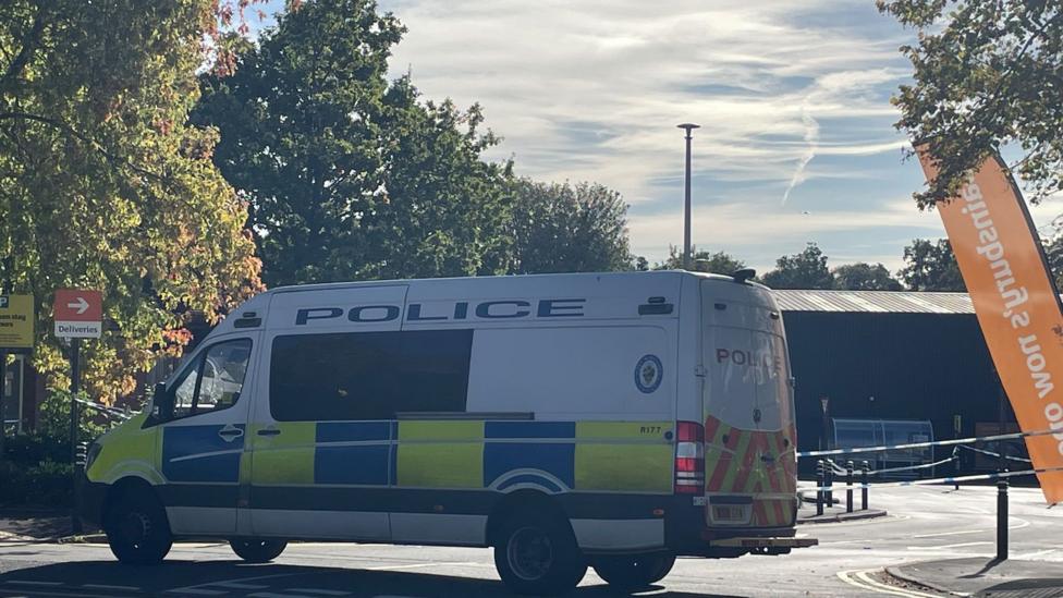A police van parked at the entrance of a supermarket