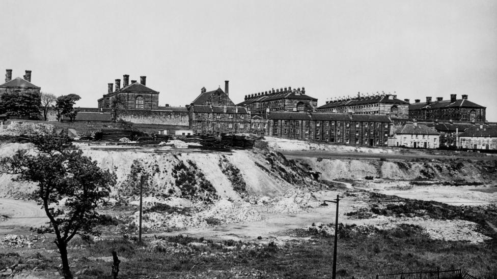 Black and white photo of Victorian prison blocks next to a quarry