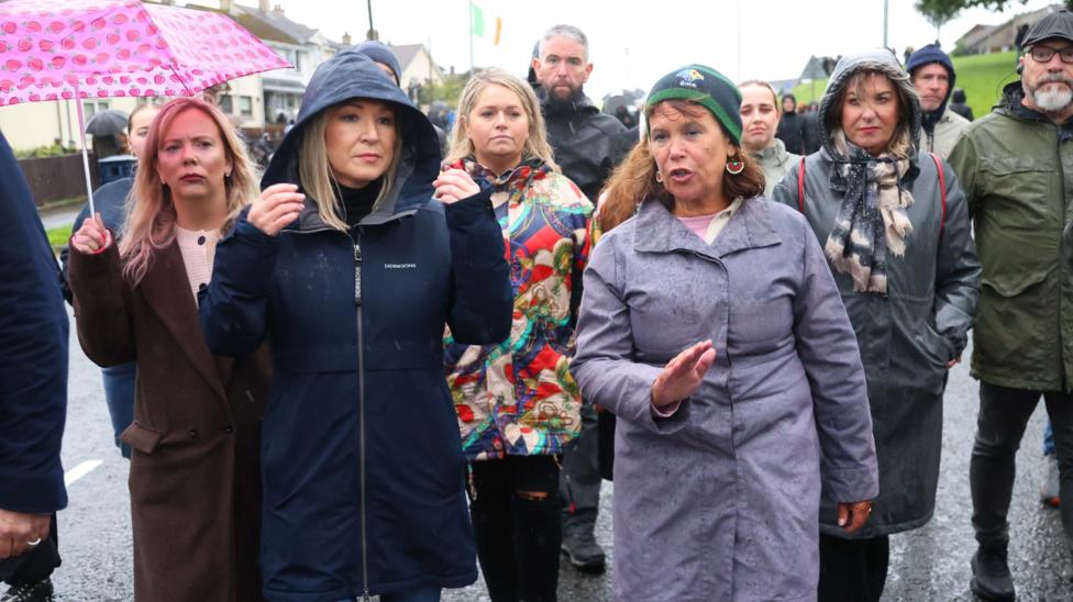 A crowd of people walk down the Garvaghy Road