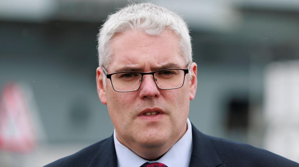 A man with white hair wearing glasses and a suit
