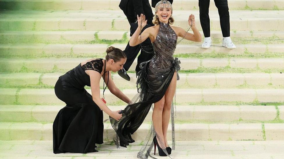 An assistant adjusts Sabrina Carpenter's dress at the Met Ball in New York in May
