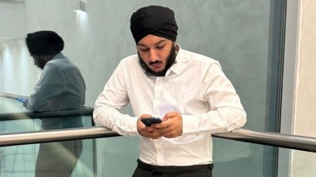 Eknoor Singh looking at his mobile phone