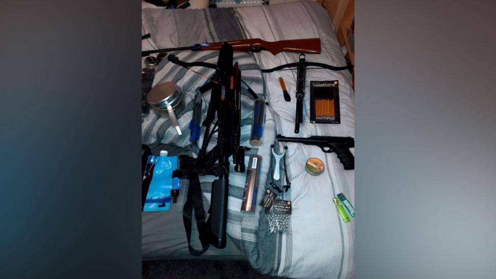 Police image of guns, bullets and other items laid on top of a bed