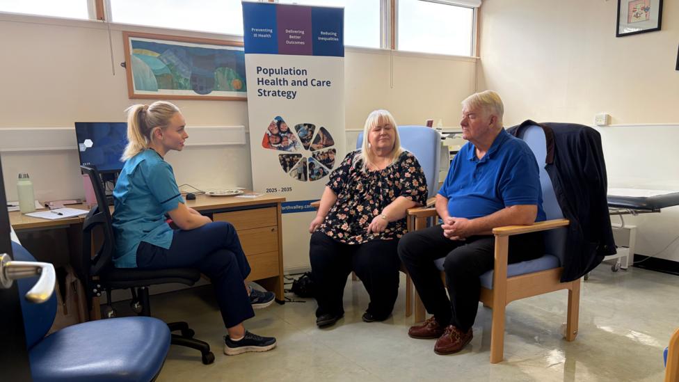 Three people sitting on chairs in a health centre