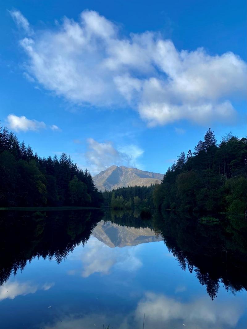 A mountain reflected in the water with trees on either side