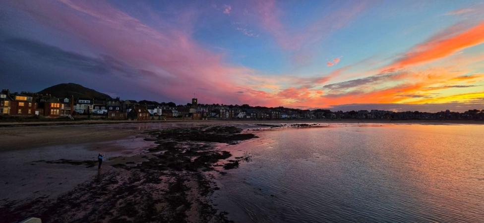 A colourful sunset in a wide-angle photo of a beach