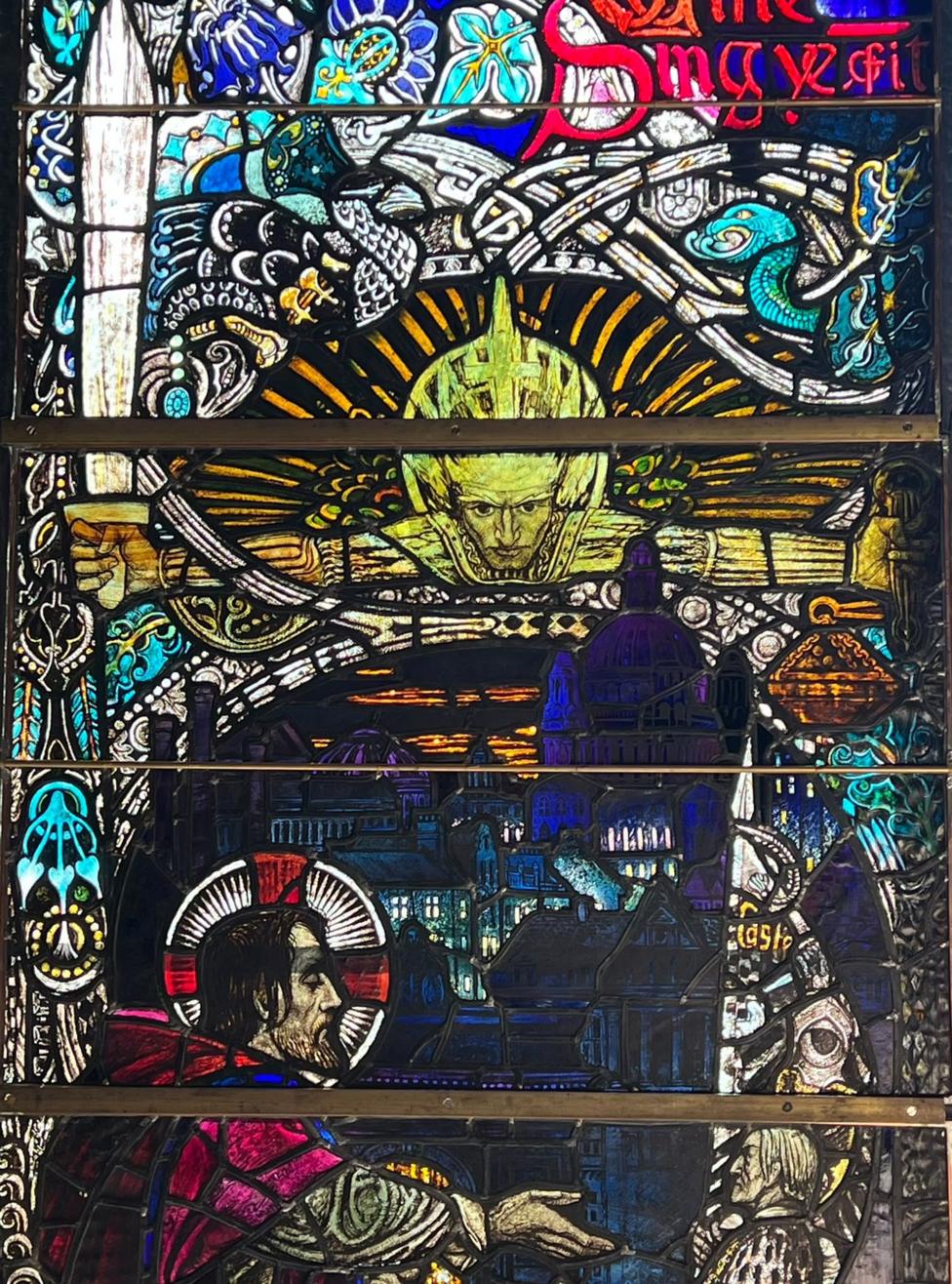 Intricate stained-glass artwork with red jewel-like glass and religious symbolism.