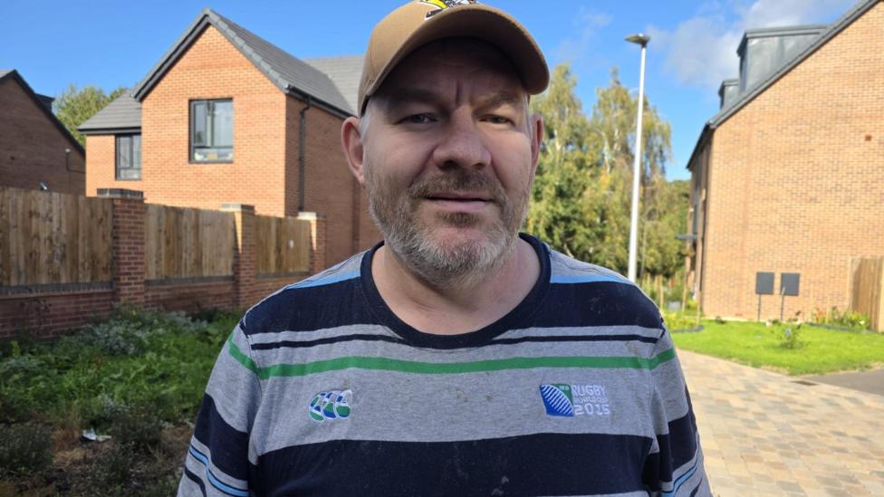 A man in a Rugby World Cup 2015 teeshirt, with blue and grey stripes.
