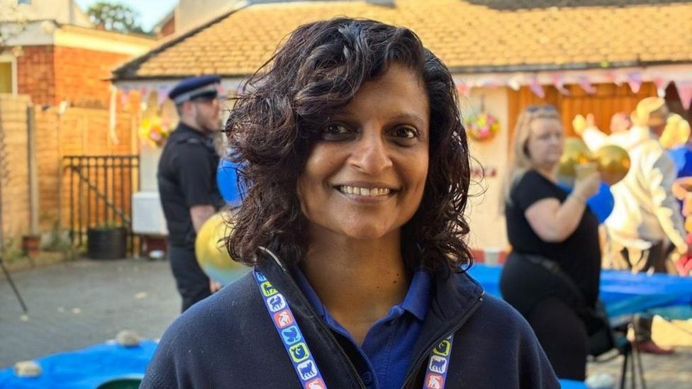 Imara Ó Niocail, smiling for the camera in a small courtyard decorated with party decorations. She is wearing an RSPCA lanyard with the outlines of animals on it.