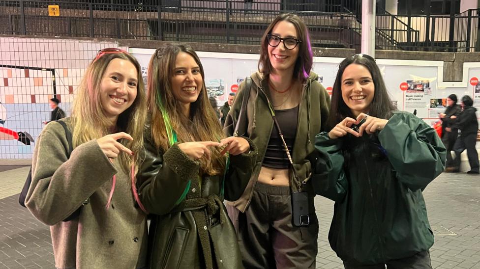 Four women pose with two making heart symbols with their hands
