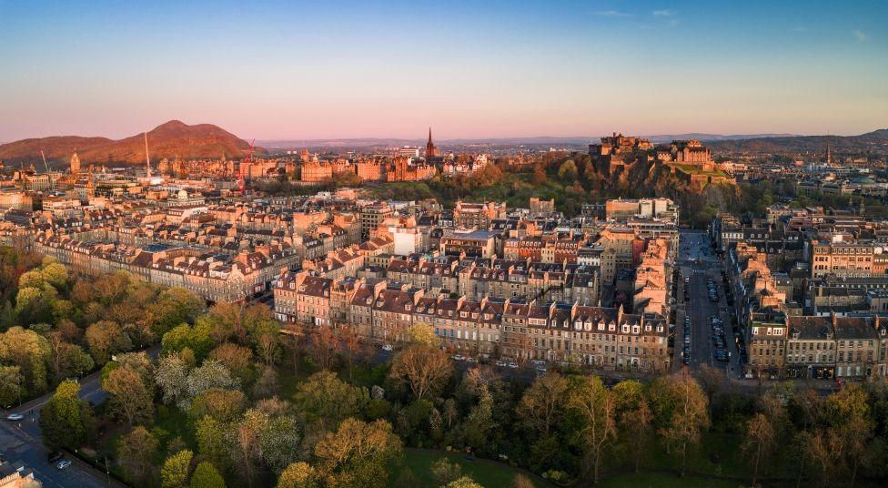 An ariel view of Edinburgh city centre at sunset with Arthur's Seat and Edinburgh Castle in the background