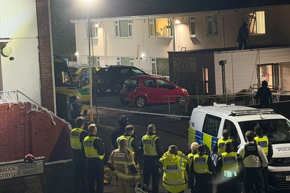 Police officers outside a street. It is a housing estate.