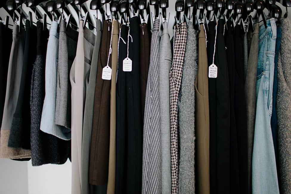 A close-up image of a row of skirts and trousers hanging on a rail, in different fabrics and patterns.