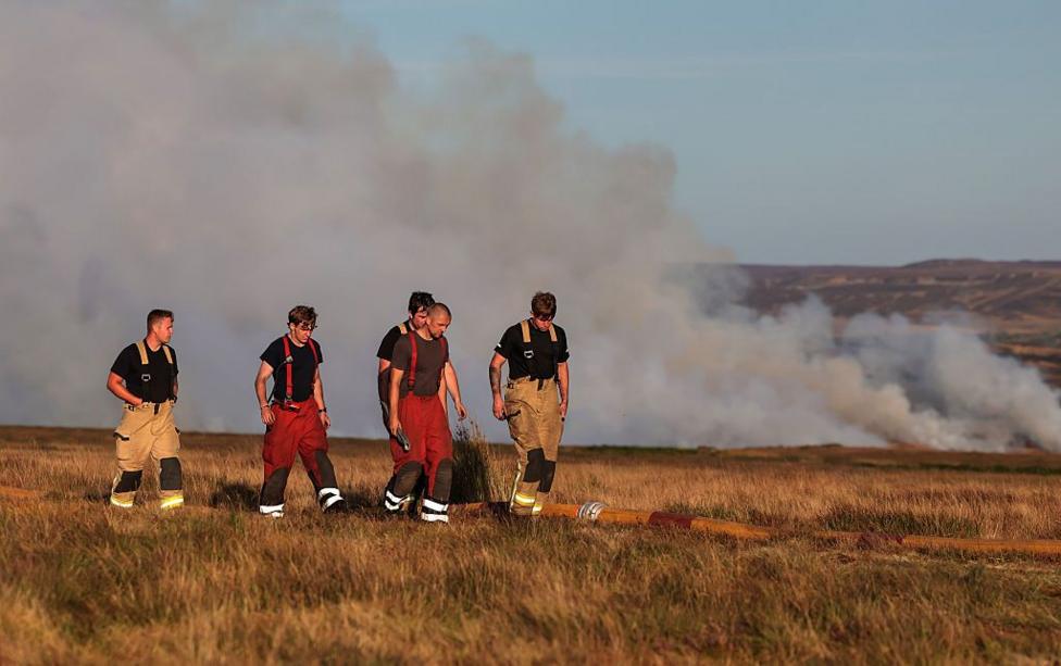 Staff walk back to base as firefighters from the Mid and West Wales and South Wales Fire Services fight wildfires on Llangynidr Moor which was declared a major incident.