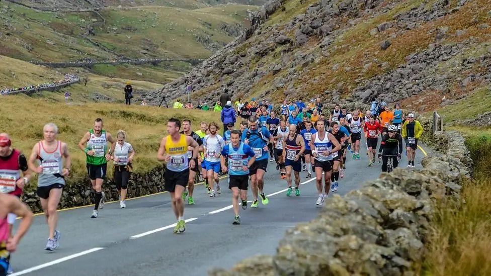 Runners travelling up a road in the mountains of Eryri.
