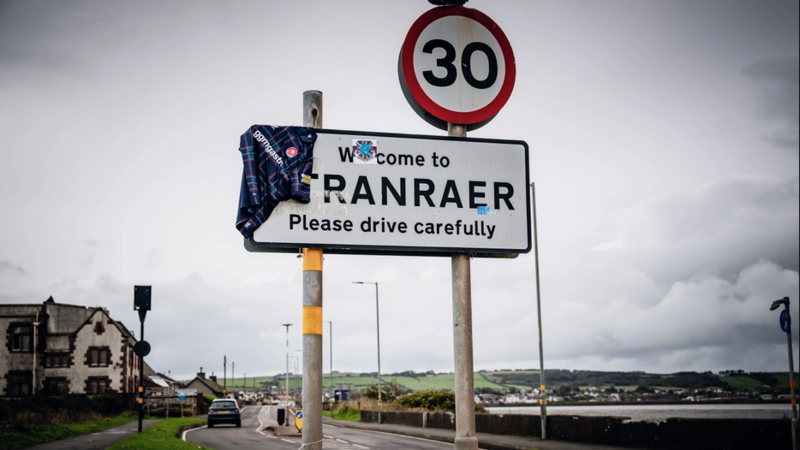 The tartan shirt hanging over the side of a sign reading 'Welcome to Stranraer'.