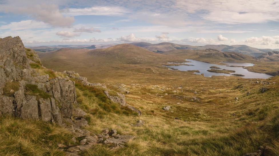 A view across hilly ground towards a loch