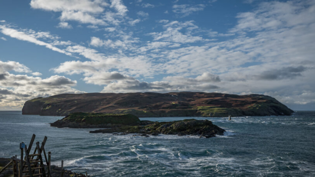 in the distance of the image you can see a brown island below cloudy skies