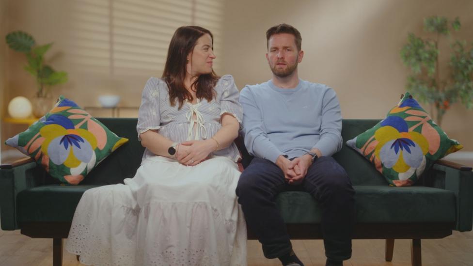 Kate and Matt are sitting on a green couch during an interview for One Born Every Minute in this candid still from the film footage.