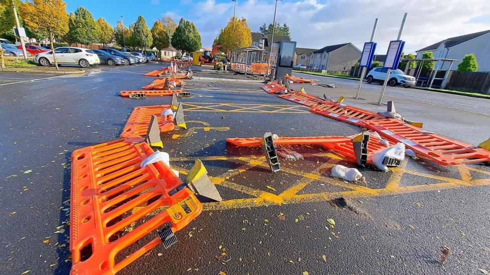 The plastic barrier are bright orange and lie on the ground in a car park around disabled parking spaces.