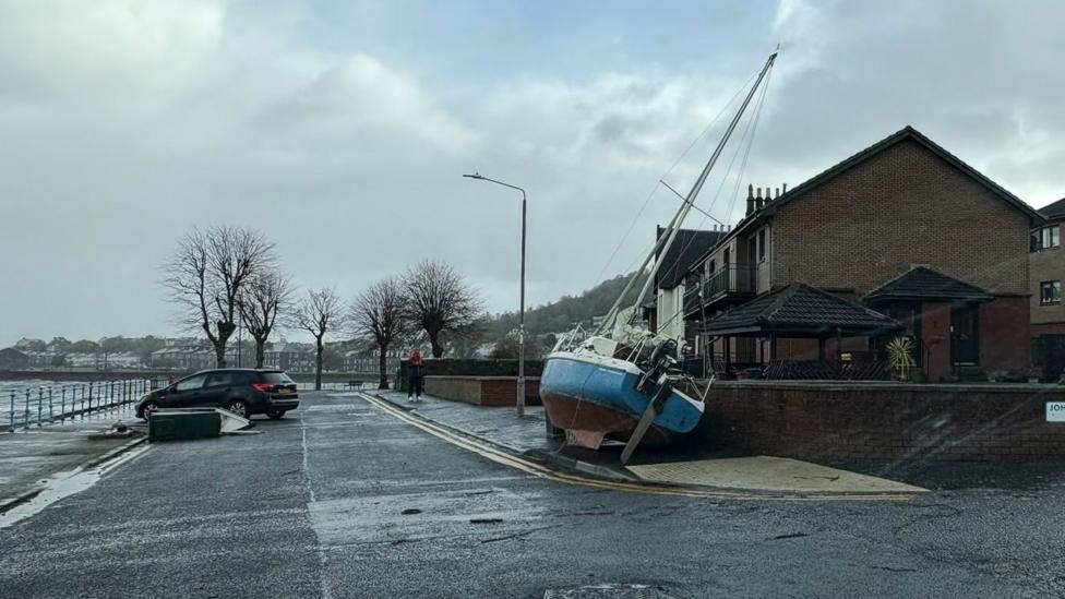 A blue hulled sailing boat rests against a wall in Gourock.