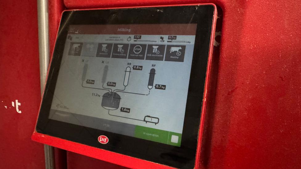 A milking machine screen on a red wall.