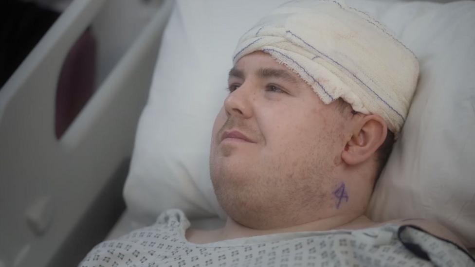 A man with a bandage around his head lying in a hospital bed.