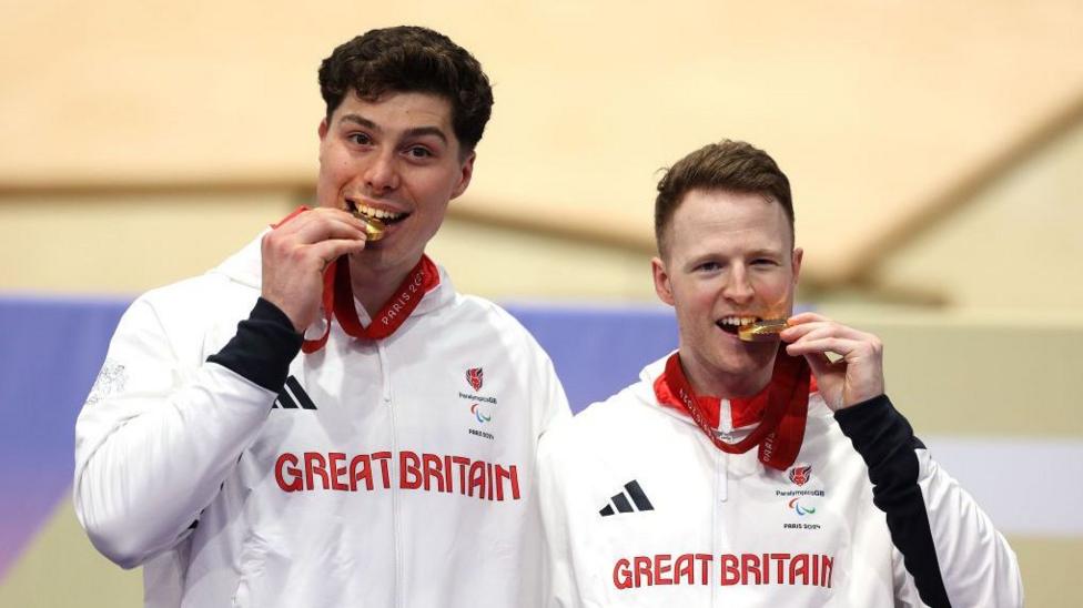 Pilot Steffan Lloyd and James Ball of Team Great Britain celebrate on the podium after the Para-cycling track men's B 1000m time trial medal ceremony at the Paris 2024 Paralympics