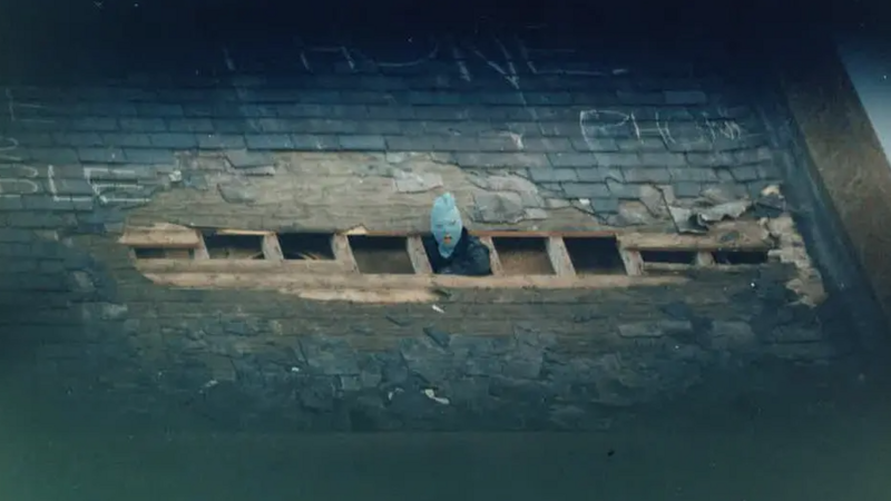 A masked prisoner poking their head out the broken roof of Peterhead prison during a riot in 1987.