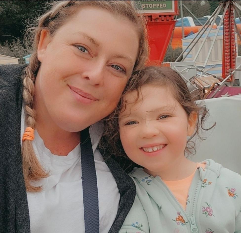 Laura Miller, a woman with blond hair in a ponytail, smiles for the camera alongside her daughter Grace, who is also smiling.