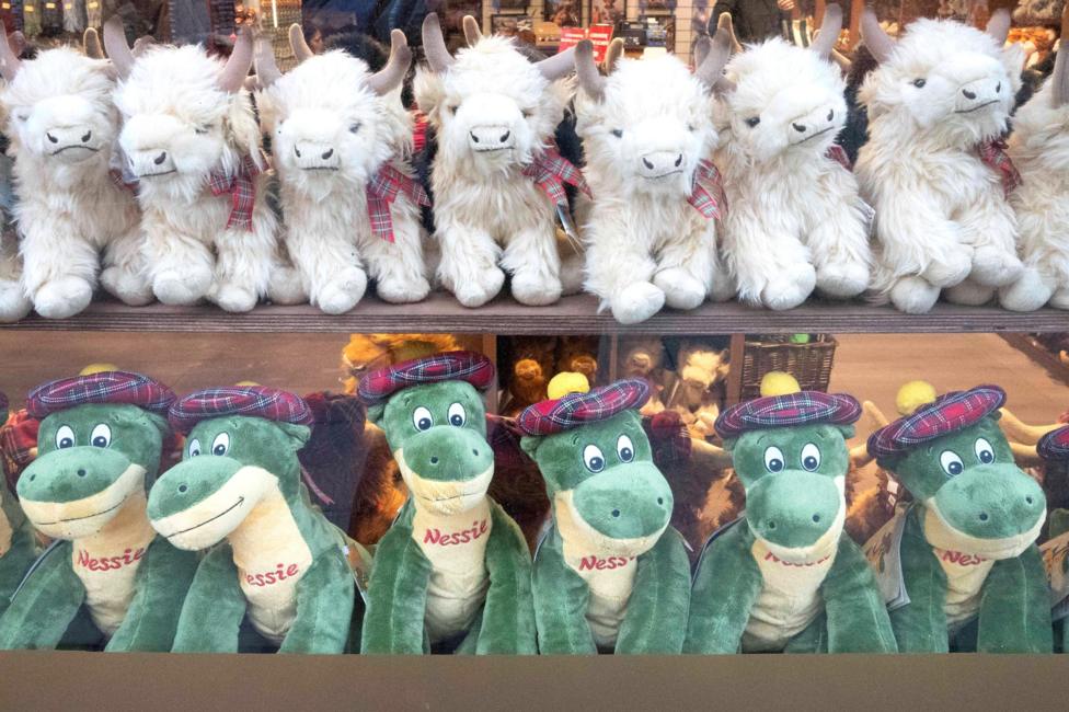 A shop window with fluffy toy Highland cows and Nessie monsters.