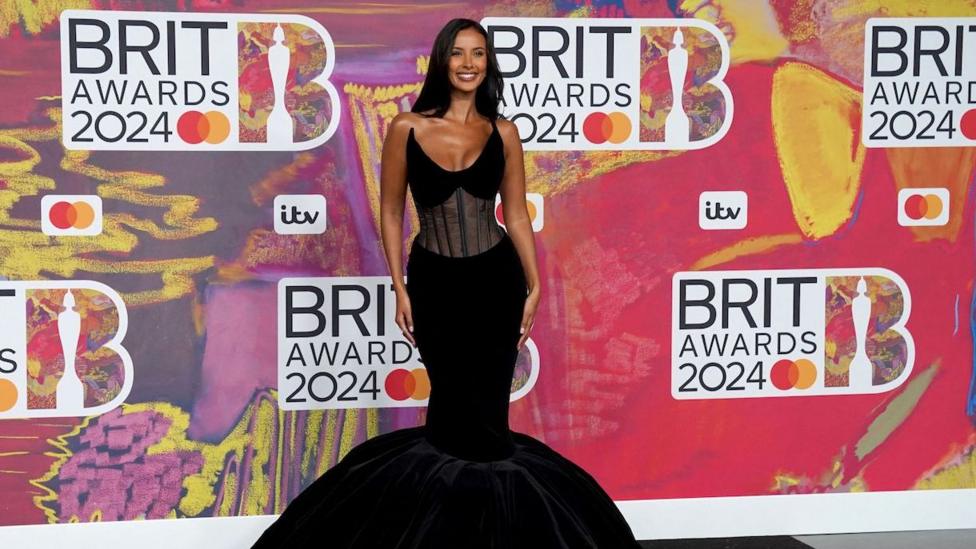 Maya Jama on the red carpet wearing a long, strapless black dress at the 2024 Brit Awards.