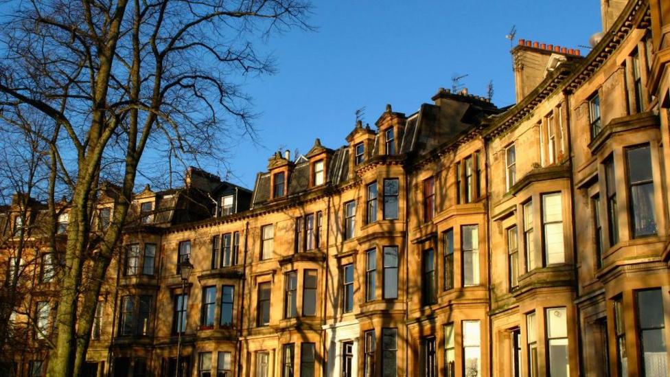 A row of blonde sandstone tenement buildings in Glasgow.